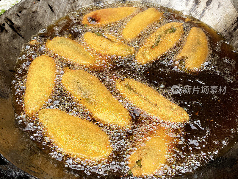 全帧图像烹饪绿色辣椒油饼(mirch pakora)，在大锅热油油炸，印度街头小吃摊贩，印度街头小吃摊档，不健康的饮食，高架视图